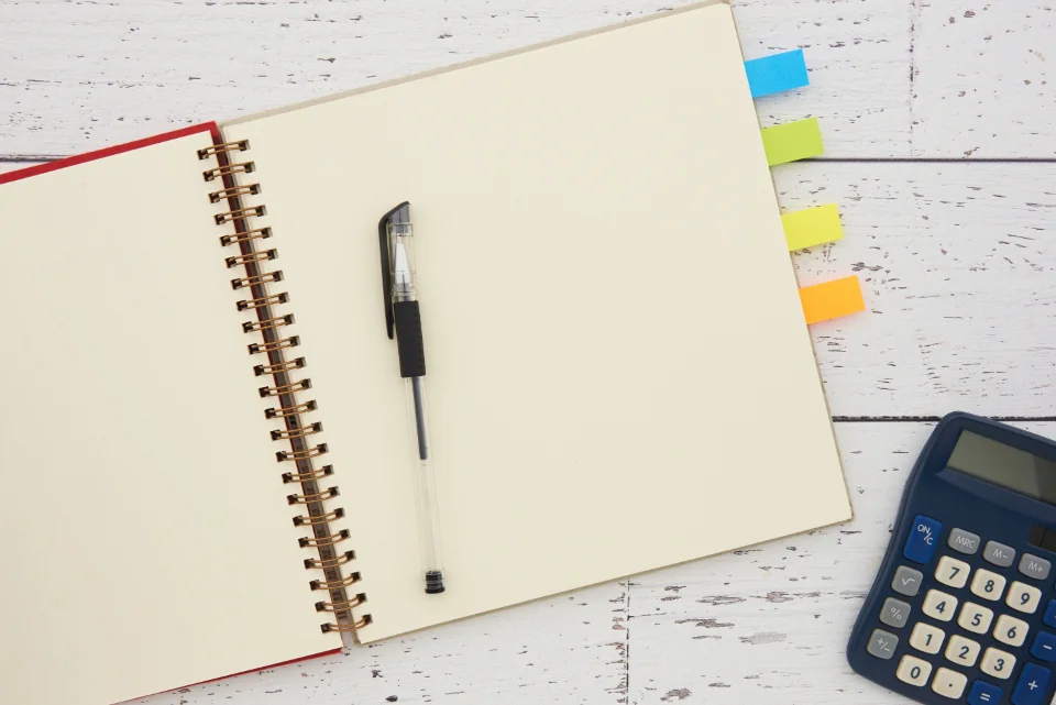 Notebook, pen, and calculator arranged on a desk.