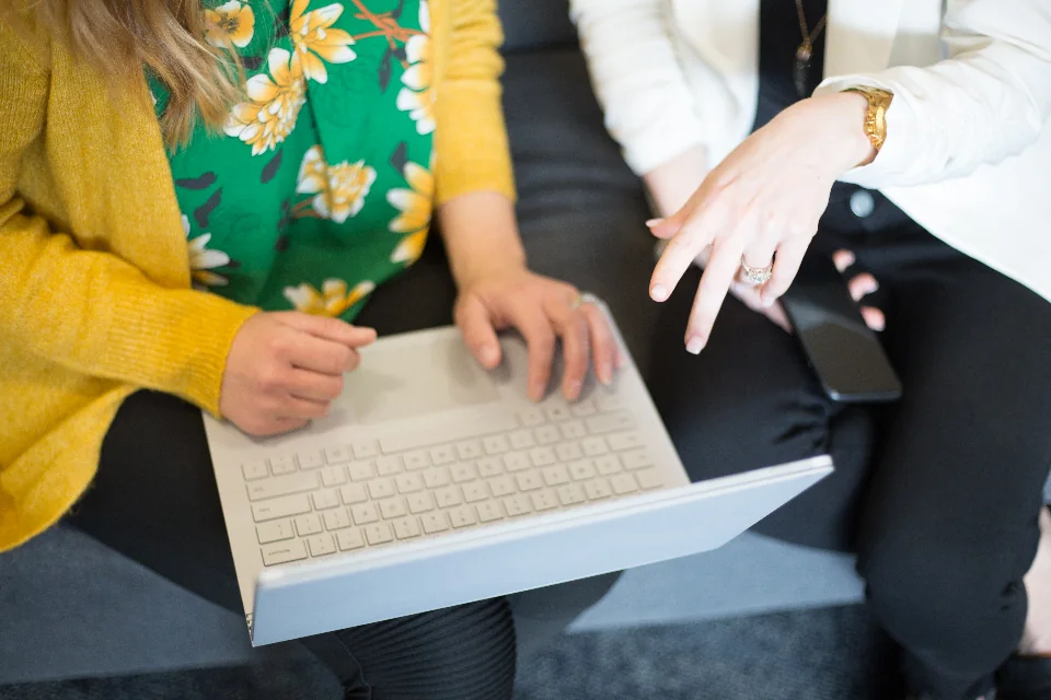 Colleagues discussing work together around a laptop.