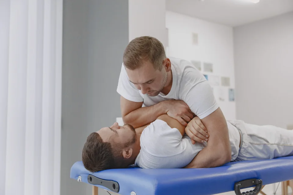 Practitioner performing a manual back examination on a treatment table.