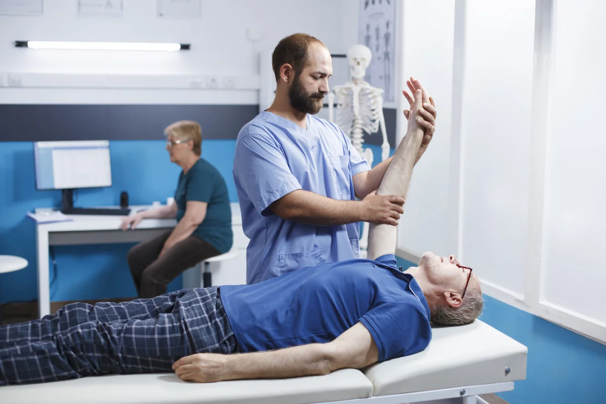 Practitioner providing manual arm treatment to a fully clothed client.