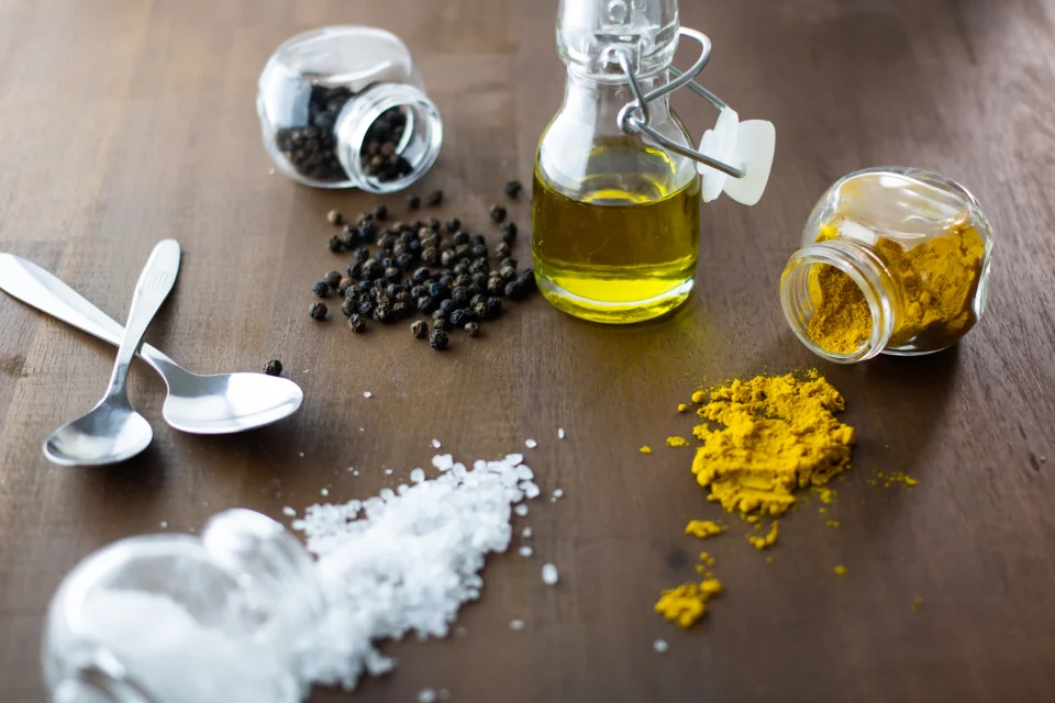 Salt, spices, and oil arranged for food preparation.