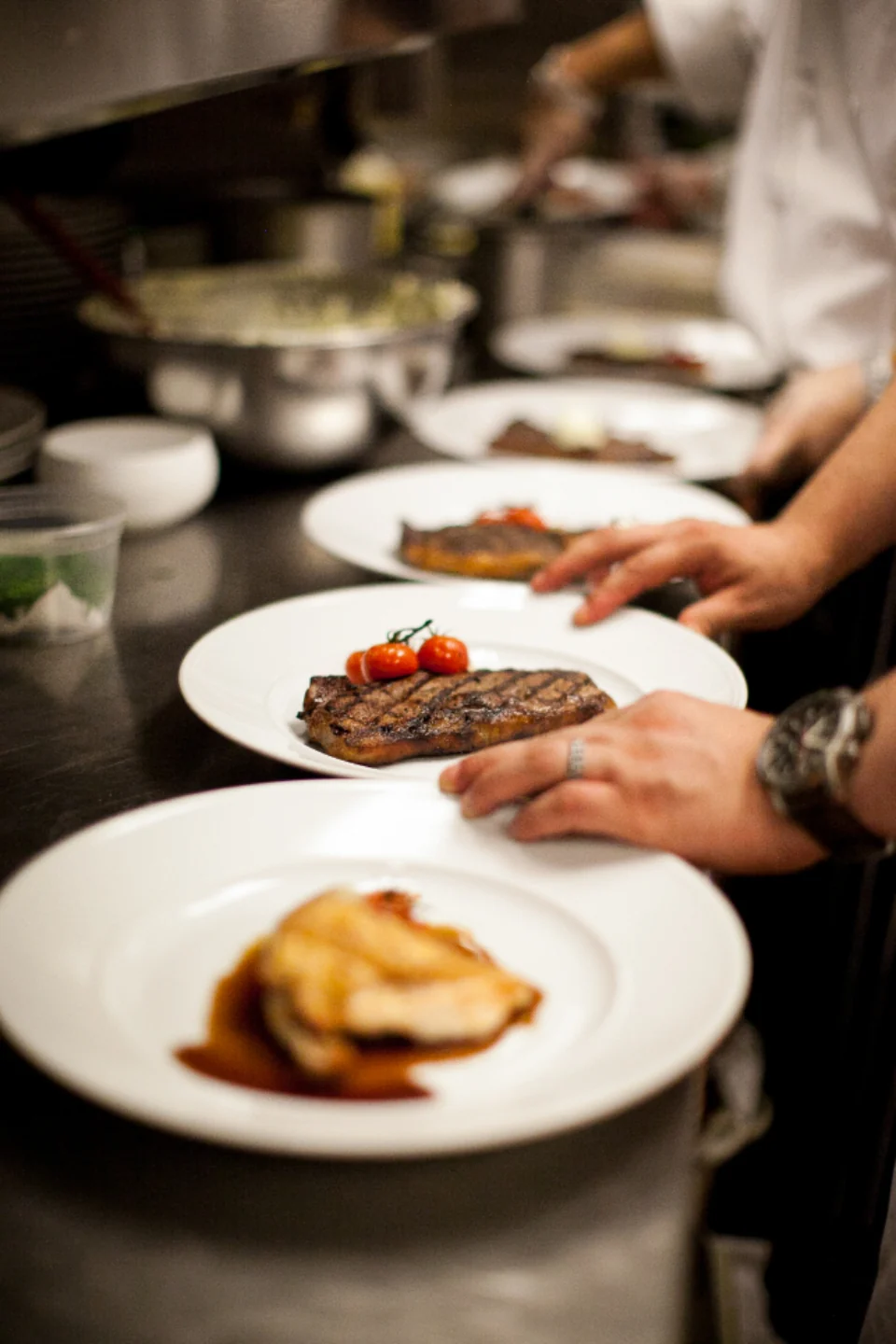 Chefs preparing plates in a restaurant kitchen.