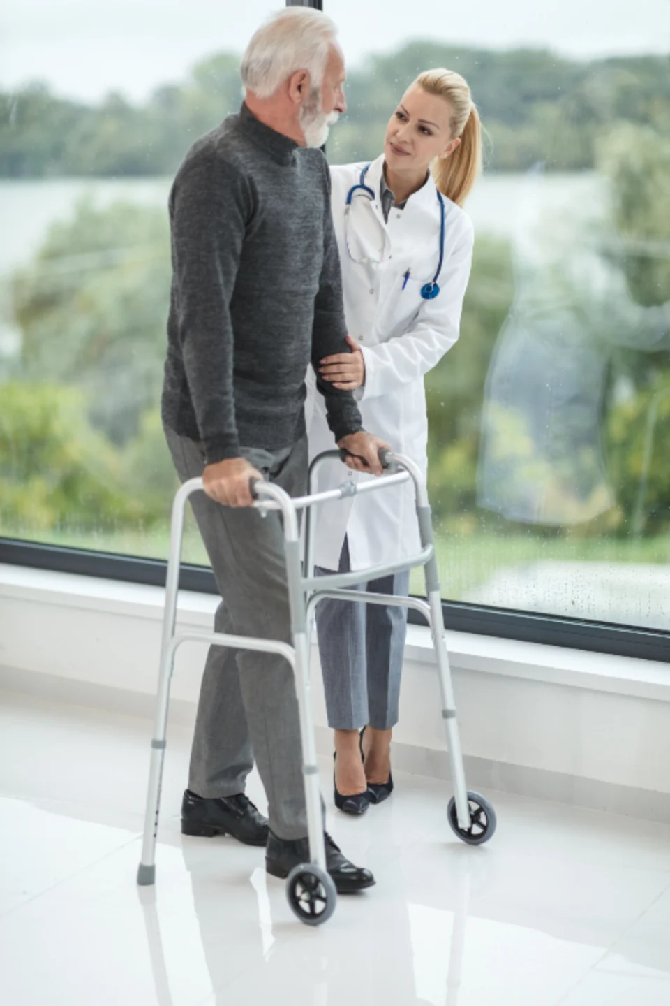 Healthcare worker assisting an older adult with a walker.